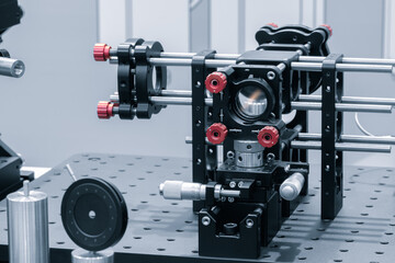 Leinwandbilder - Optical equipment including telescope and lenses are displayed on a table in a laboratory. Optics and photonics concept science experiment with laser background.