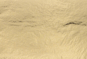 Aufkleber - Golden foil texture with metallic, pearlescent shimmer creates a subtle, elegant finish. Soft light highlights the smooth, polished surface, perfect for luxury wrapping, art, and upscale decor..