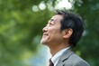 © nikolettamuhari - A middle-aged Japanese man wearing business casual attire is smiling and looking up at the sky in