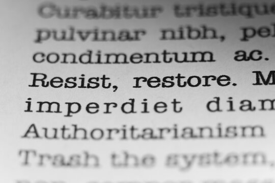 Resist, Restore. Text printed on a page. A piece of paper with a phrase written in retro typewriter font.