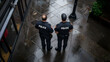 © kang - Two Police Officers in Uniform Standing on a Wet City Street