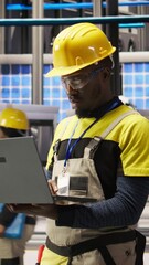 Poster - vertical video portrait of smiling technician in solar panels factory oversees robot assembly lines,
