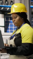 Poster - vertical video technician in eco friendly industrial plant monitors production equipment using noteb
