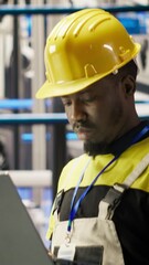 Poster - vertical video smart solar panels factory technician using laptop to oversee conveyor belts. african