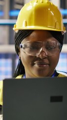 Poster - vertical video smiling smart factory engineer typing on laptop, overseeing monitoring of production 