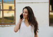 © Anastasia.photoyoga - Beautiful long hair woman happy talking on mobile phone in white dress on the street house. Closeup relaxing emotional face portrait outdoors on summer city background