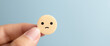 © Yeager arts - A hand gently cradles a small wooden disc depicting a sad face, conveying feelings of quiet disappointment against a serene pale blue backdrop.