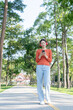 © Thitisak - Asian woman walks and listens to music in a public park.