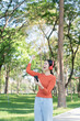 © Thitisak - Asian woman walks and listens to music in a public park.