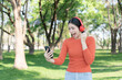 © Thitisak - Asian woman walks and listens to music in a public park.