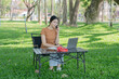 © Thitisak - Asian woman sitting using laptop, working in a park