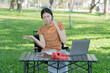 © Thitisak - Asian woman sitting using laptop, working in a park