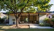 © Cherrin - Accessory dwelling unit concept. Modern home with large windows surrounded by lush greenery and a tree in the yard.
