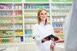 © bnenin - Friendly Female Pharmacist Assisting a Customer in a Modern Pharmacy Environment