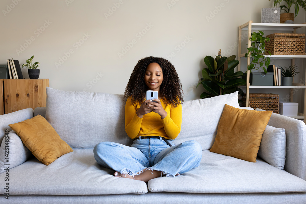 Foto African American woman using mobile phone relaxing at home living ...