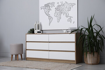 Poster - Dresser with different decor and pouf near grey wall indoors. Interior design