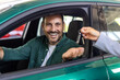 © Graphicroyalty - Dealer handing car key to businessman with electric SUV in background inside car dealership, symbolizing sustainable transportation, vehicle purchase, and business success.
