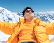 © Lailatul - Man in yellow jacket relaxes in snowy mountains, arms outstretched, enjoying sun