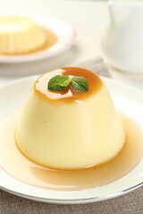 Wall Mural - delicious pudding with caramel sauce and mint on table, closeup