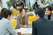 © boyhey - A group of Japanese business people meeting and discussing in an office.