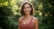 © schiers_images - The woman has short, dark hair and is wearing a reddish-brown tank top, standing in front of a blurred background of greenery, with sunlight shining down on her and creating a warm glow.