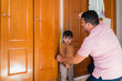 © pablo - Father measuring his son's height with a tape measure on a wooden door frame, checking his growth progress