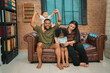 © chokniti - Heartwarming family moment as an African American father and daughter share playful time together on the couch, surrounded by love, laughter, and the warmth of home, while mom gently looks on with joy