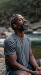 Poster - A man experiences tranquility by the riverside, eyes closed, breathing deeply while soaking in the peaceful surroundings and natural beauty of the landscape.