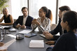 © fizkes - Business discussion. Young Black female sit at boardroom table express opinion on briefing with diverse polyethnic teammates offer idea of finance investment share plan of company growth at brainstorm