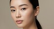 © Katsyarina - Close up portrait of young asian woman with smooth clear skin looking at camera on neutral background. Headshot for beauty cosmetics banner, spa salon poster.