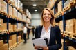 © NikoG - Middle aged businesswoman smiling holding a clip board in a distribution warehouse