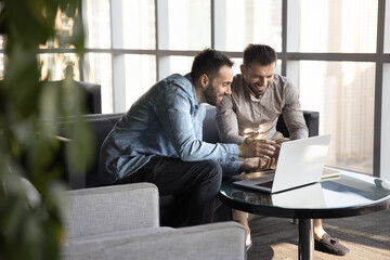 two smiling multiethnic teammates, business partners watching video on laptop, learning new ai busin
