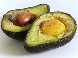 Two halves of a ripe avocado are seasoned with salt and pepper and each contains a perfectly cooked egg yolk.