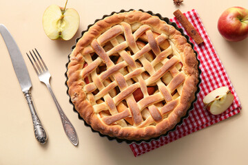Wall Mural - tasty homemade apple pie with fruits, cinnamon and cutlery on beige background
