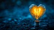 © Harry - Glowing Heart Shaped Lightbulb Romantic Idea Inspiration Warm Yellow Light Dark Blue Background Creative Design Element Abstract Photography Still Life Image Perfect for Valentines Day Wedding
