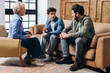 © Maria Vitkovska - Father and teenage son talking with female psychologist sitting on sofa in the office