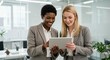 © Optimax Image - Two Businesswomen Collaborating on a Tablet in a Modern Office