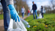 © Curioso.Photography - Volunteers wearing gloves picking up litter in a park during a community cleanup event.