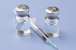 © warunthorn - Glass Vials with Liquid and Syringe on Blue Background for Healthcare