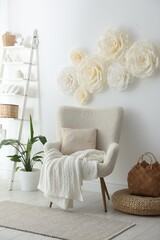Poster - Beautiful decorative paper flowers on white wall and stylish furniture indoors