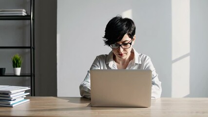 Poster - Focused female accountant meticulously preparing tax returns, diligently working on a laptop in a contemporary office setting, surrounded by organized documents and bathed in natural light