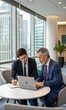 © DND - Two busy professionals collaborating in an office, working on a laptop. A corporate meeting where a bank manager consults a company client. (People)
