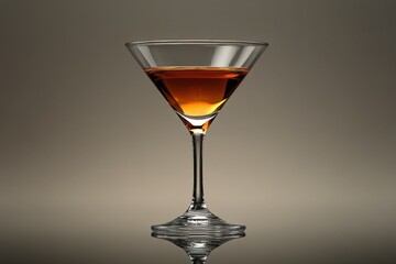 Poster - Elegant cocktail glass with amber drink reflecting on a smooth surface in a dimly lit setting