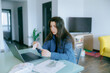© Alexandr - Woman Managing Household Finances and Bills at Home with Laptop