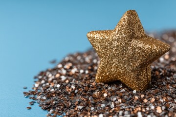 Aufkleber - Glittering gold star surrounded by shimmering black and copper particles on a blue background
