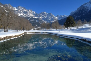 Poster - Snow-covered mountains reflect in clear water under a bright blue sky in a tranquil alpine landscape during winter