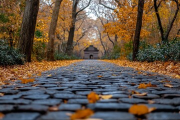 Poster - Pathway lined with autumn leaves leads to a historic structure in a tranquil park setting