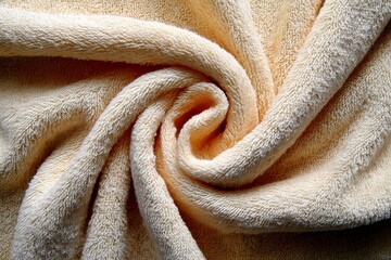 Poster - Soft yellow towel elegantly arranged in a spiral shape capturing light and texture during daytime