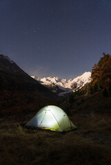Fototapete - A tent under the night sky in the moonlit Bernina mountain group, Switserland.