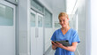 © Monkey Business - Female Doctor Wearing Scrubs In Hospital Corridor Using Digital Tablet